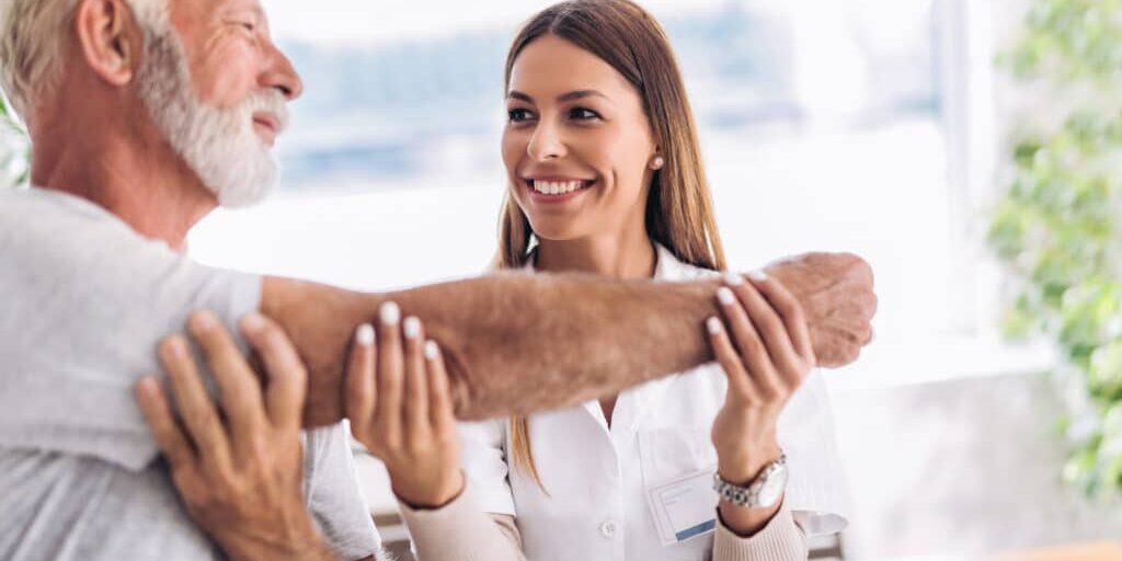 Man having chiropractic arm adjustment. Physiotherapy, sport injury rehabilitation. Senior man exercises in center for chiropractic.