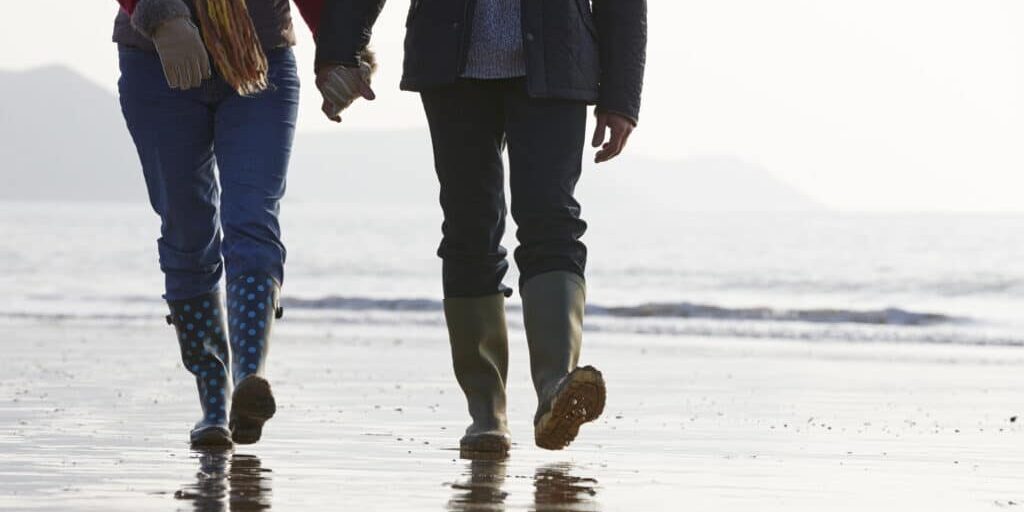 Close Up Of Senior Couple Walking Along Winter Beach